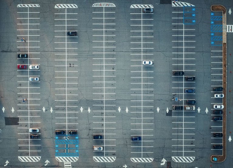 An aerial view of parking lot with cars and road marks